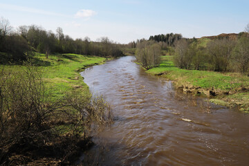 Naklejka premium Tranquil River Flowing Through Lush Green Countryside In Spring