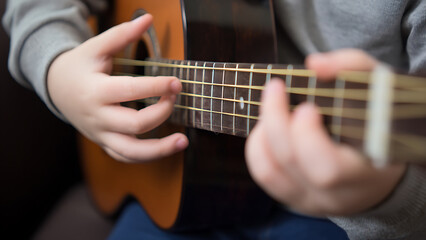 Fototapeta premium Close-up of a person playing an acoustic guitar, focusing on hands and strings.
