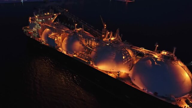 Aerial of Liquified Natural Gas LNG carrier moored to a small gas terminal at night. Fuel crisis. Sanctions
