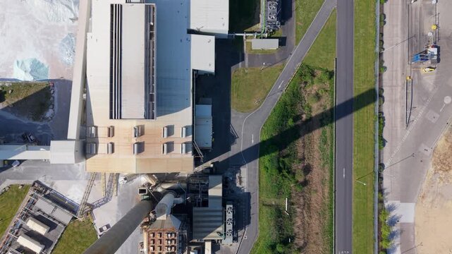 Aerial view of the Guardian Glass Production Factory with its large chimney casting a long shadow over the industrial site in Goole, England, United Kingdom.