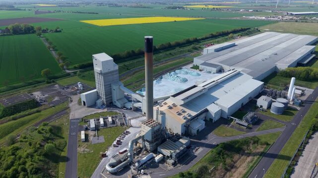 Aerial view of the Guardian Glass Production Factory with its tall chimney and surrounding green fields in Goole, England, United Kingdom.