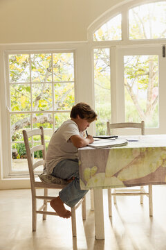 12 year old boy doing homework at kitchen table 