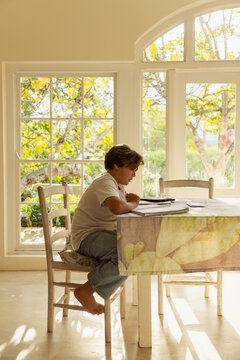 12 year old boy doing homework at kitchen table 
