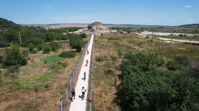 Aerial view of Solnitsata prehistoric salt production center with people on a long path surrounded by green fields and trees in Provadia, Varna, Bulgaria.