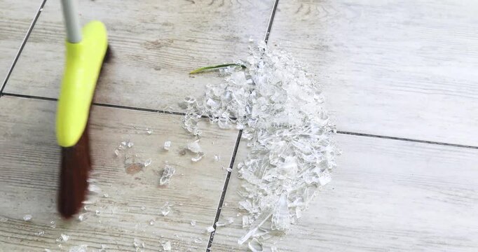 Sweep small pieces of broken glass from kitchen tiles with a broom to avoid cuts.