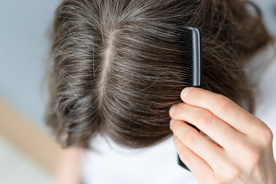 Close up of a woman whose gray hair stems from her long struggle with depression. The mature adult sees physical manifestation of mental pain in strands. Mother traces silver to suffering.