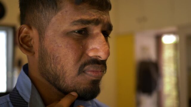 Young Indian male in office college attire adjusts tie while staring into a mirror, unhappy with acne-ridden tanned skin; an intimate bedroom moment reflecting self-image concerns and insecurity