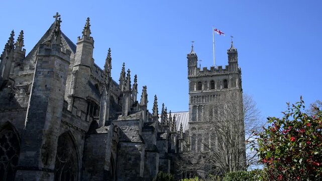 Exeter cathedral in Devon, England. Famous Exeter landmark with a blue sky background and flag flying. Religion and worship video.