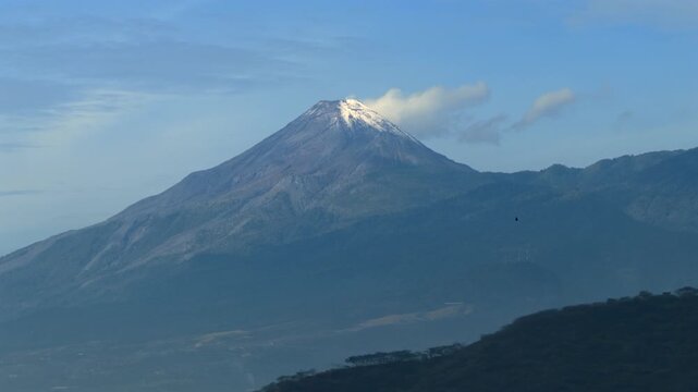 Volc&aacute;n de Colima cone with snow covered summit and rugged volcanic slopes near Colima, Mexico. Slow aerial motion.