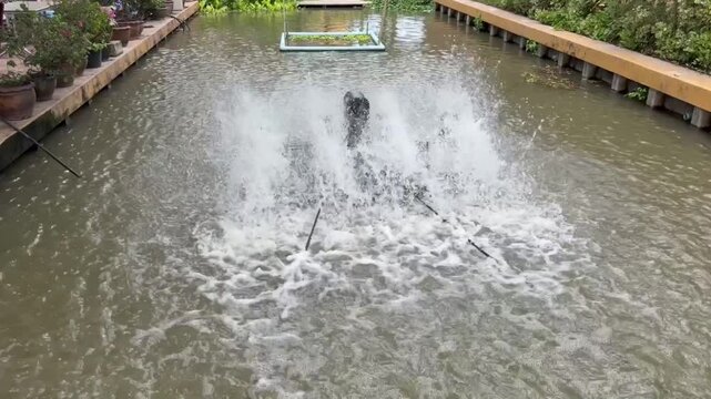water turbine aerator splashing water in canal to increase oxygen. Wastewater treatment machine working in outdoor pond, sustainable agriculture and environmental technology in Thailand
