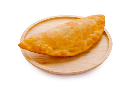 Freshly baked empanada served on a wooden plate in a kitchen setting