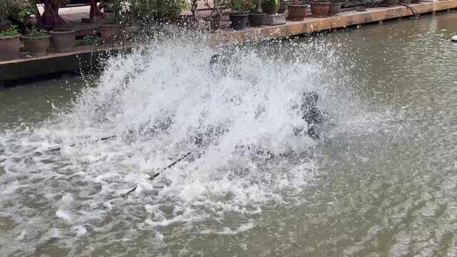 water turbine aerator splashing water in canal to increase oxygen. Wastewater treatment machine working in outdoor pond, sustainable agriculture and environmental technology in Thailand