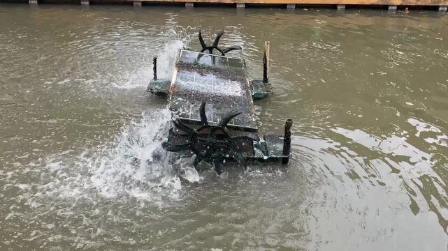 water turbine aerator splashing water in canal to increase oxygen. Wastewater treatment machine working in outdoor pond, sustainable agriculture and environmental technology in Thailand