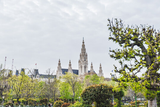 Vienna City Hall spires visible through lush spring trees in Volksgarten park