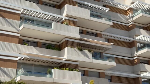 Close up detail of a contemporary luxury residential building facade with geometric balconies, terraces and glass railings in Madrid, Spain.