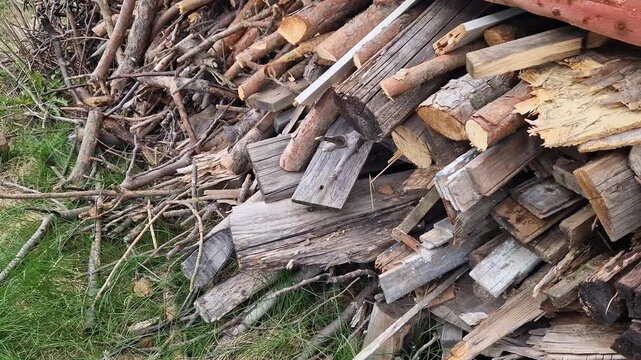 Pile of dry brushwood and firewood close-up. Wooden branches and logs prepared for a campfire. Detailed plan of a pile of dry branches and a stack of firewood. Concept of heating or outdoor recreation