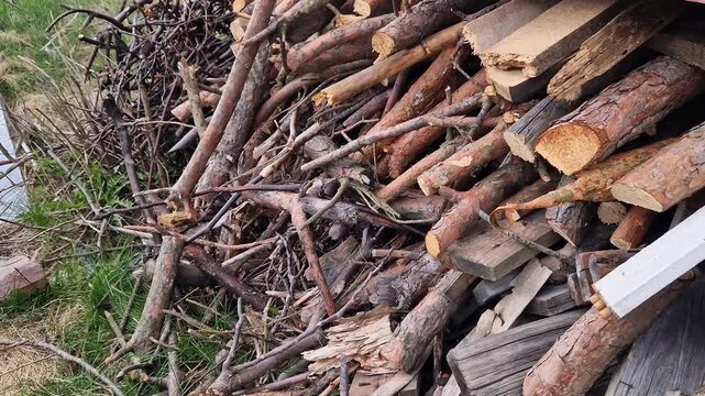 Pile of dry brushwood and firewood close-up. Wooden branches and logs prepared for a campfire. Detailed plan of a pile of dry branches and a stack of firewood. Concept of heating or outdoor recreation