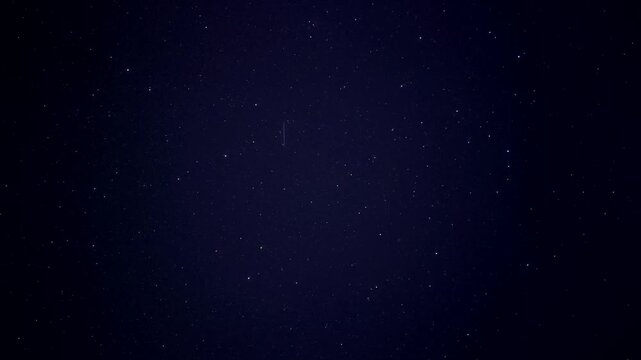 Celestial astrovideo showing meteor streak across dense starfield night