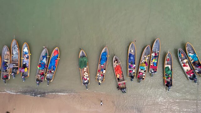 Aerial view of colorful wooden boats filled with supplies and people along the sandy shoreline in Wewak, East Sepik Province, Papua New Guinea.