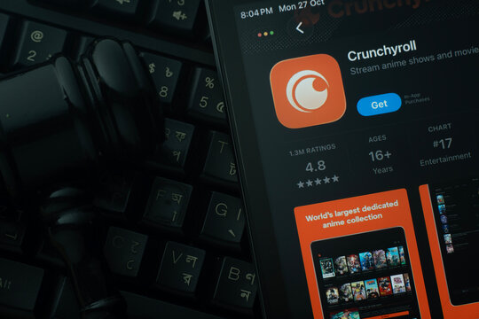 Dhaka, Bangladesh- 28 Oct 2025: An iPad displaying the Crunchyroll app against a judge's gavel and dark keyboard background.