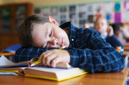 Education, boy or tired with sleeping in classroom for learning fatigue, boring lesson or burnout. Books, child student or nap at elementary school for low energy, academic workload or study pressure