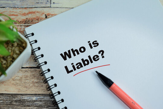 Concept of who is liable write on book isolated on Wooden Table