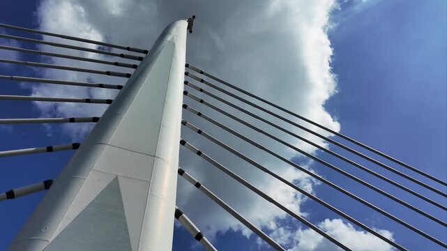 Detailed low angle view of the modern Halic Metro Bridge pylon and steel cables under a blue sky with clouds in Istanbul, Turkey.