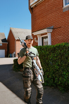 Man walking with hedge trimmer after yard work in neighborhood
