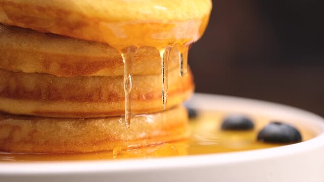 Pancakes stack with dripping honey syrup and blueberries