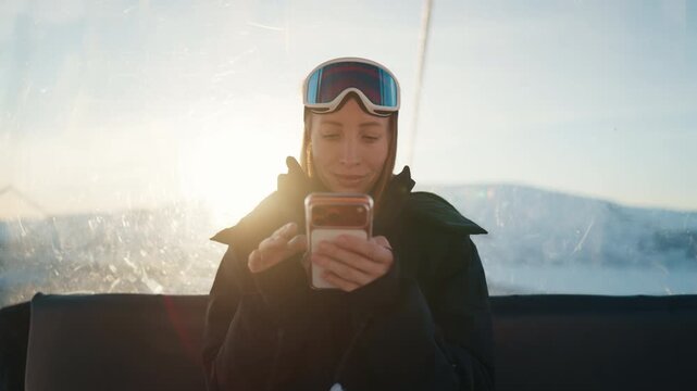 Good internet and mobile net coverage area, use smartphone at top of mounts. Woman skier or snowboarder riding cable car in modern luxury ski resort, watching pictures on screen, phone addiction