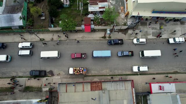 Aerial view of vehicles and pedestrians moving along a city street with shops and houses in Wewak, East Sepik Province, Papua New Guinea.