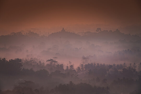 Misty Morning view of Borobudur with layers of trees seen from Setumbu, Indonesia