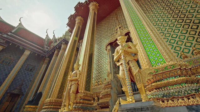 Golden guardian statues and ornate temple facade at Wat Phra Kaew in Bangkok, traditional Thai architecture in Thailand