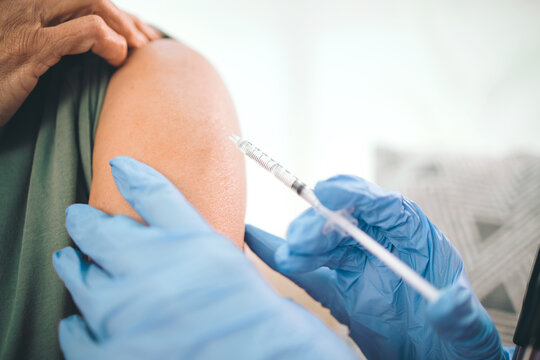 Arm, injection and hands of nurse with needle in home for vaccine, virus safety or medical treatment. Syringe, gloves and healthcare worker with patient for vitamin shot at consultation in house.