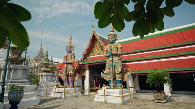 Giant guardian demon statues at Wat Phra Kaew temple complex in Bangkok Thailand with colorful traditional architecture