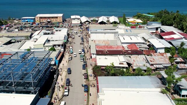 Aerial view of the coastal town of Wewak with cars on the street, buildings under construction, and the blue sea in the background in Wewak, East Sepik Province, Papua New Guinea.