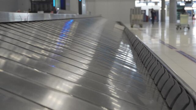 Baggage claim conveyor belt in an airport terminal with metallic surface reflecting belt plate emputy of any luggage bag, showcasing the continuous flow of luggage belt at airport without any luggage