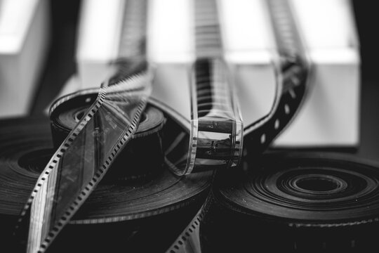 Black and white close-up of vintage photographic film rolls and negatives, symbolizing analog photography and classic film production