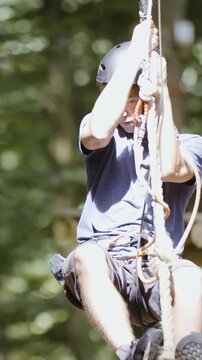 Person slide on rope zip-line towards the camera in slow motion