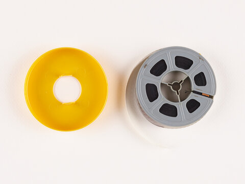 Anciennes bobines de 8 mm et Super 8. Une bobine de film vintage qui se d&eacute;roule, mettant en valeur la beaut&eacute; du cin&eacute;ma analogique. Fond uni et simple.