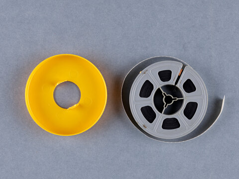 Anciennes bobines de 8 mm et Super 8. Une bobine de film vintage qui se d&eacute;roule, mettant en valeur la beaut&eacute; du cin&eacute;ma analogique. Fond uni et simple.