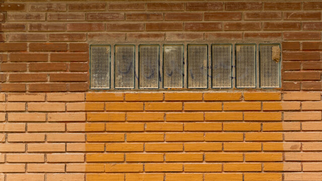 Industrial brick wall with glass block window and weathered facade