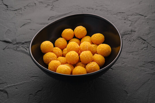 Snack balls in a black bowl on a textured surface at a kitchen table