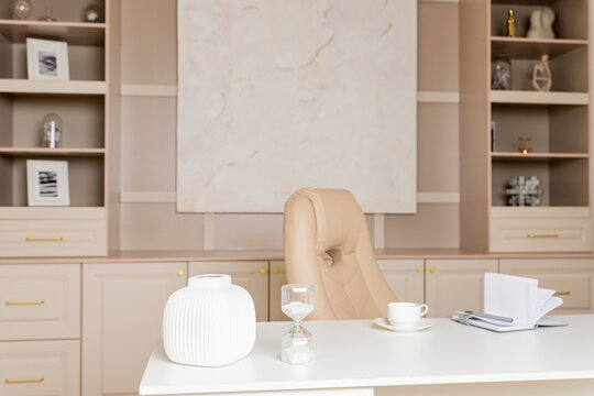 Beige leather chair, laptop and desk in office.Modern workplace.Stylish workplace with laptop, cup of coffee. elegant personal accessories in home decor.