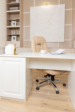 Beige leather chair, laptop and desk in office.Modern workplace.Stylish workplace with laptop, cup of coffee. elegant personal accessories in home decor.