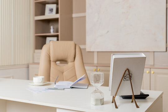Beige leather chair, laptop and desk in office.Modern workplace.Stylish workplace with laptop, cup of coffee. elegant personal accessories in home decor.