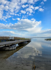 Obraz premium Wooden pier on a calm lake under a blue sky with clouds