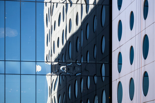 Reflections hover over circles pattern in modern glass facade where the building architecture becomes an abstract corporate background graphic