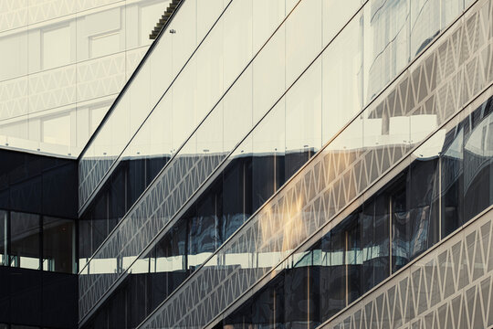 Diagonal pattern meets sunlight on modern glass facade giving the building architecture a corporate edge and an abstract background feel