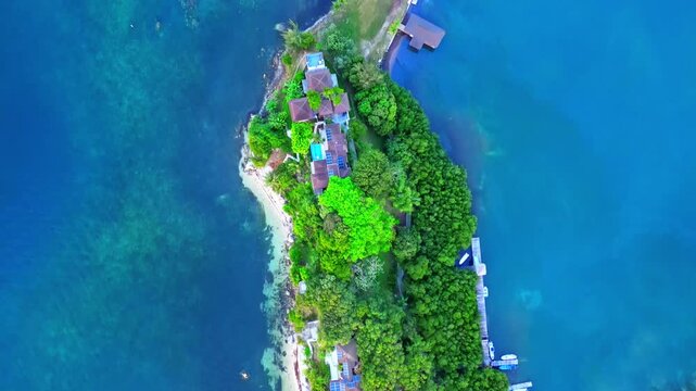 Aerial view of tropical houses nestled among lush green trees and turquoise waters in Sandy Bay, Bay Islands Department, Honduras.